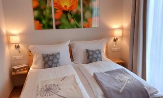 A cozy bedroom with two single beds and soft lighting. Blooming plant pictures hang on the wall, giving the room a friendly atmosphere.