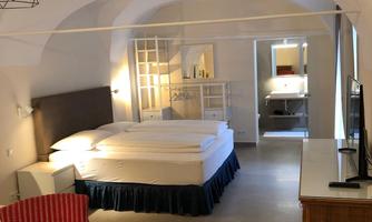 A cozy room with a large bed and a red armchair. The room has light walls and a modern look.
