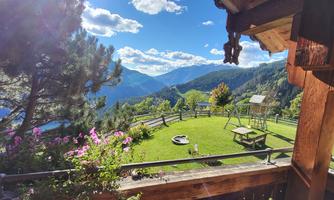 A picturesque mountain landscape with green meadows and blooming flowers. The sky is clear and sunny, perfect for relaxing days outdoors.