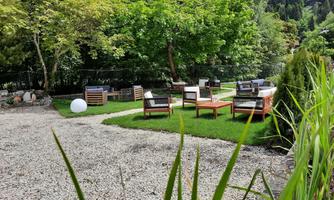 A cozy outdoor area with wooden seating areas and green lawn. Surrounded by trees, the space offers a relaxed atmosphere.