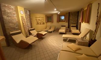 A quiet room with loungers and soft lighting. The walls are designed with stone and warm colors, creating a relaxing atmosphere.
