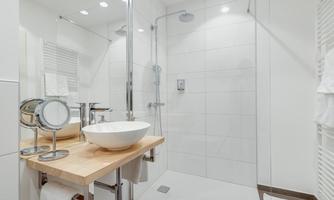 A modern bathroom with a shower cubicle and a ceramic sink. Bright tiles and clean lines create a tidy, elegant atmosphere.
