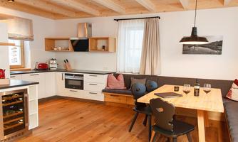 A modern kitchen with a wooden ceiling and a cozy dining area. Bright colors and a friendly atmosphere characterize the space.