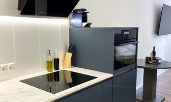 A modern kitchen with an elegant kitchen island and black appliances. The room is bright and friendly, with wooden flooring.