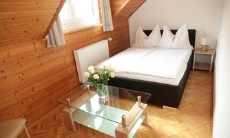 A cozy bedroom with a double bed and wood paneling. A glass table with a flower vase creates an inviting atmosphere.