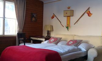 A cozy bedroom with a large bed and colorful pillows. On the wall are decorative elements and a window with curtains.
