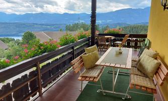 A cozy terrace with wooden chairs and a table. In the background, mountains and a picturesque landscape can be seen.