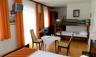 A simple room with a loft bed and a dining area. Large windows let in plenty of daylight.