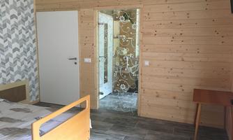 A cozy room with a wooden frame and modern wallpaper. In the background, a door can be seen that leads to another room.