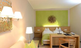 A modern hotel room with simple furniture and soft colors. The walls are painted in neutral tones, and there is pleasant lighting.