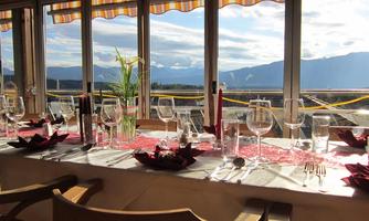 An elegantly set table with glassware and decorative napkins. In the background, mountains and a clear sky are visible.