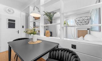 A modern living environment with a black table, stylish chairs, and bright walls. Plants and decorative elements create an inviting atmosphere.
