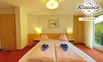 A modern room with a double bed and romantic decoration. Large windows provide a view outside and plenty of daylight.