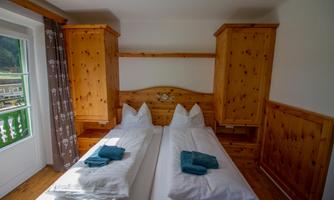 A cozy bedroom with two beds and wooden shelves. Towels are placed on the beds.