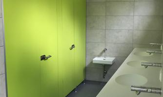 A modern bathroom with green partition walls and white sinks. The walls are designed to be bright and simple.