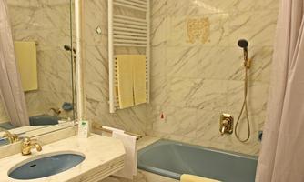 A bathroom with a marble pattern, a bathtub, and a modern sink. The walls are light, and there are towels in soft colors.