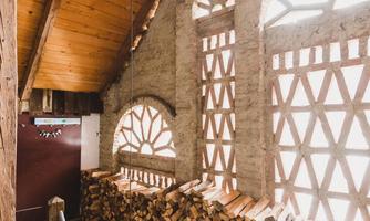 A cozy wooden cabin with windows in a unique pattern and a woodpile. The space has a warm, inviting atmosphere.