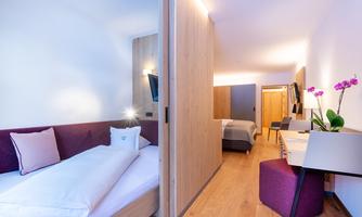 A modern hotel room with wooden floors and cozy furnishings. The rooms are bright and stylishly decorated with an elegant orchid.