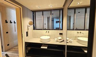 A modern bathroom with a large, elegant sink and towels. The rooms are brightly lit and feature stylish black accents.