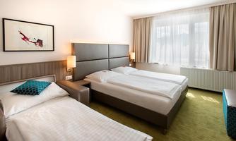 A modern hotel room with two beds and decorative pillows. Large windows provide plenty of daylight.