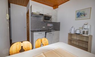 A modern kitchen with wooden details. There is a table, kitchen utensils, and a microwave visible.
