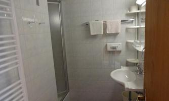 A modern bathroom with a shower, sink, and towel holders. The walls are tiled, and the floor is equipped with blue tiles.