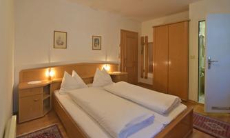A simple bedroom with a double bed and two nightstands. The room has a bright atmosphere and wooden furniture.
