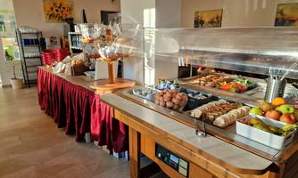 A breakfast buffet with various foods, including fruit, eggs, and bread. The atmosphere is bright and inviting.