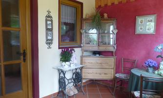 A cozy entrance area with a wooden terrace and colorful walls. A table with flowers and furniture in rustic style create an inviting atmosphere.