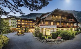 A charming hotel in the mountains with traditional architecture. Surrounded by green landscape and a clear sky.