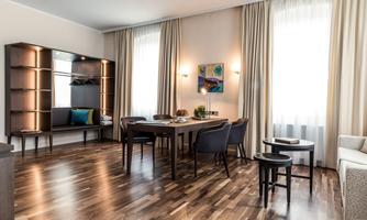 A modern living room with a large table and elegant chairs. Bright windows let in plenty of light and create a pleasant atmosphere.