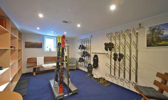 A modern ski room with shelves for skis and boots. The room is brightly lit and has a cozy seating area.