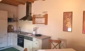 Modern kitchen with wooden shelves and stainless steel appliances. A bright, inviting atmosphere with a table and chairs.