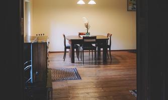A cozy dining area with a table and chairs. The room has warm lighting and a wooden floor.