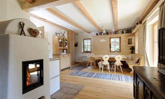A cozy living space with wooden furniture and a modern fireplace. Bright walls and large windows create an inviting atmosphere.