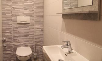 A modern toilet in bright colors with a sink and a large mirror. The walls are decorated with modern tiles.