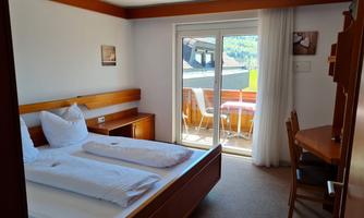 A cozy bedroom with a double bed and a balcony. The room is bright and cheerful, with a table and chairs.