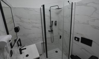 A modern bathroom with a glass shower and elegant white tiles. A sink with black fixtures is located next to the shower.