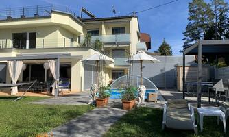 A modern house with a well-maintained garden and a small pool. There are loungers and sunshades inviting you to relax.
