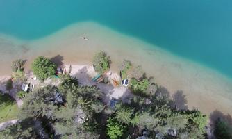 A quiet bay with clear, blue water. On the shore are some boats and trees.