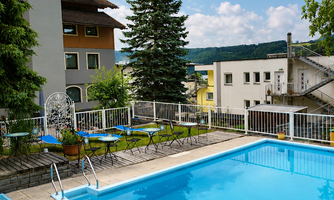An inviting pool surrounded by plants and seating areas. The sky is clear and sunny, perfect for relaxation.