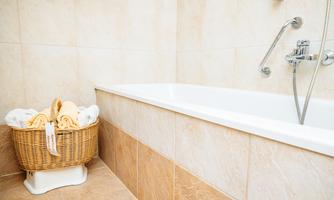 A bathroom with a bathtub and a laundry basket. The walls are in light, neutral colors.
