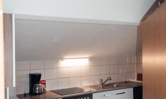 A modern kitchen with wooden furniture and white cabinets. The kitchen is well-equipped and has a space for a coffee machine.