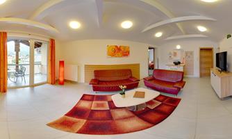 A spacious living room with two sofas and a coffee table. Large windows provide plenty of daylight and a view outside.