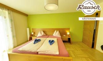 A modern bedroom with two beds and wooden flooring. The walls are designed in soft colors, and the decor is simple and inviting.