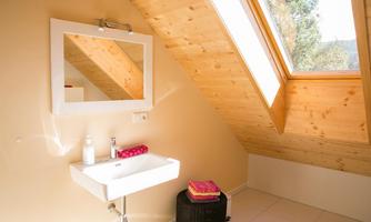 A bright bathroom with a modern sink and a large mirror. The skylights provide plenty of natural light.
