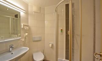 A modern bathroom with a shower, sink, and toilet. The walls are painted in light colors and there is a mirror above the sink.