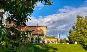 A beautiful house surrounded by green grass and trees. The sky is partly cloudy and there is a peaceful, inviting view of the landscape.