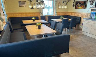 A comfortably furnished restaurant area with wood paneling. The tables are nicely decorated and there are cozy benches and chairs.