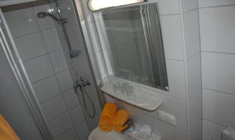 A modern bathroom with a shower and a large mirror. Yellow towels are neatly placed on the sink.
